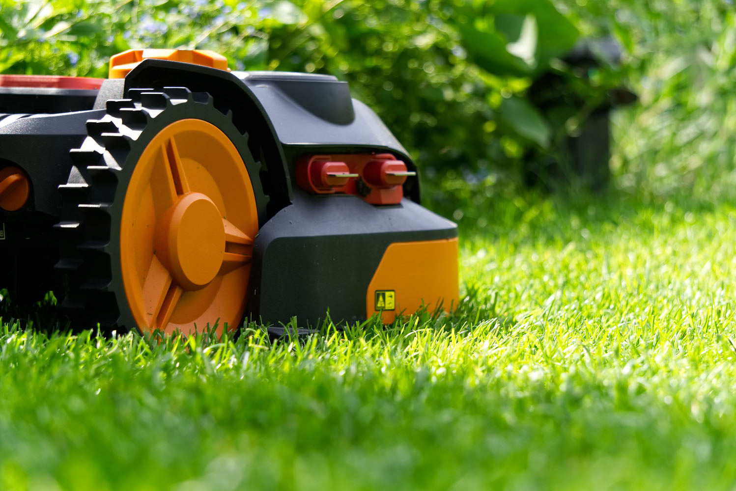 Prim-plan cu un robot de tuns gazonul, așezat pe un gazon verde