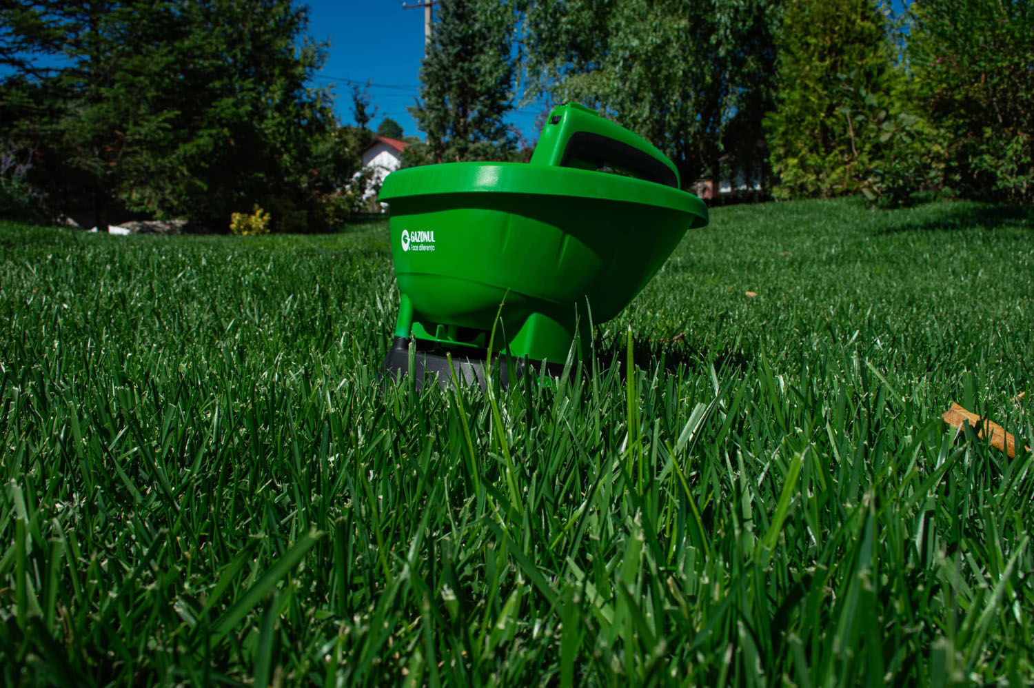 Aplicator de îngrășământ Gazonul pe o peluză verde, utilizat pentru o fertilizare uniformă și eficientă.