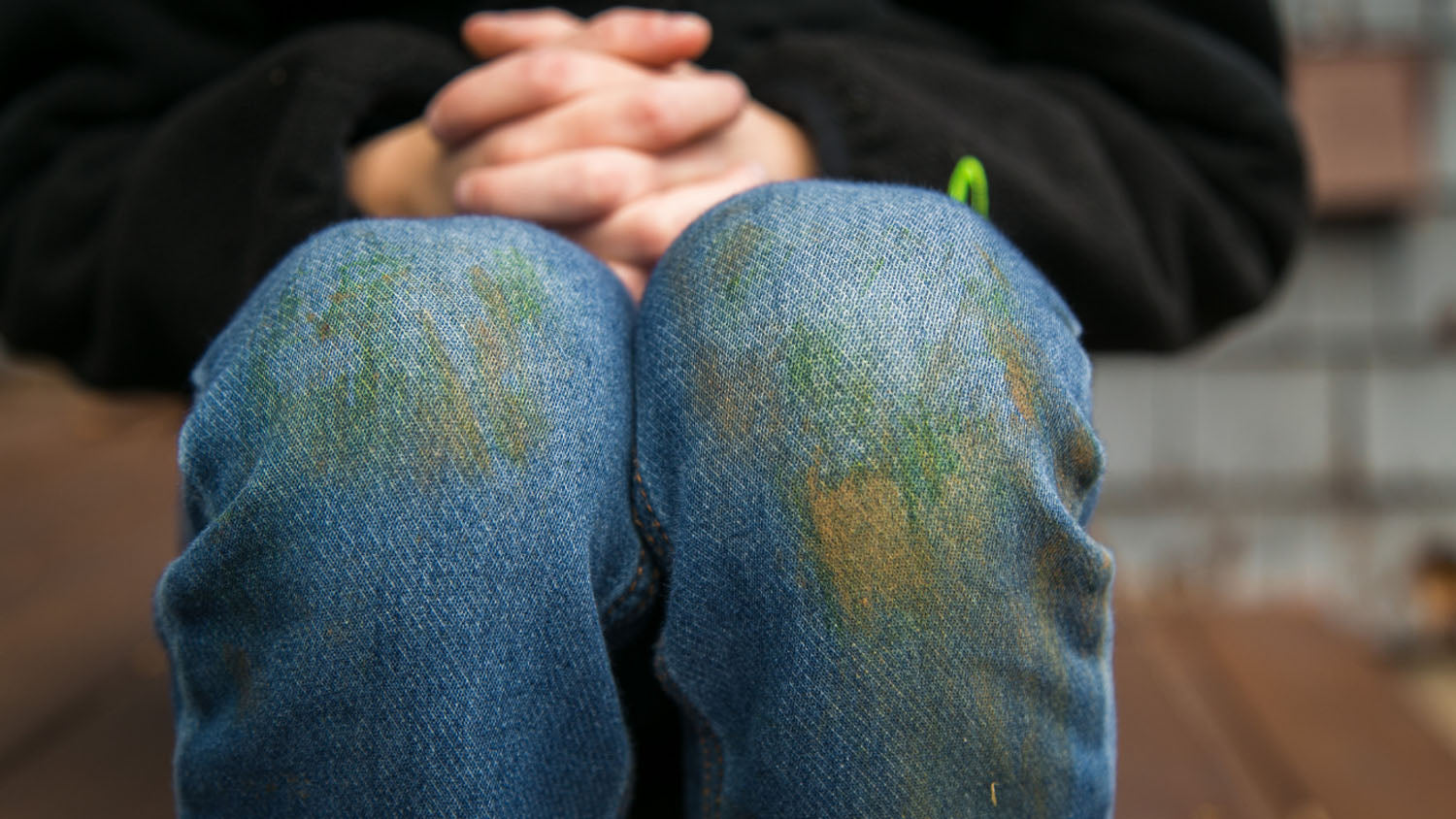 Blugi albaștri cu pete verzi de iarbă pe genunchi, semn al unei activități în aer liber sau joc pe gazon